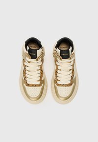 Høye sneakers med en kremaktig beige overdel, gull aksenter og en panterprintpanel. Har hvite snøringer og en svart krage.