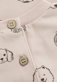 Ljusrosa bomullstyg med svarta djurmönster. Ribbad krage med rund halsringning, dekorativ knapp med två hål.