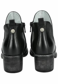 Botas de tobillo de cuero negro con un acabado liso, que presentan un tacón bajo apilado, cremalleras laterales y un acento metálico en la parte trasera.