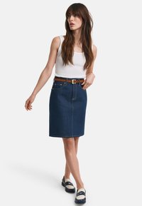 Gonna in denim scuro, lunghezza al ginocchio con taglio dritto. Abbinate a una canotta bianca e una cintura marrone. Indossate con mocassini slip-on.