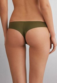 Bas de bikini en vert olive en tissu doux et extensible. Offre une couverture minimale avec une taille lisse et des bords sans coutures.