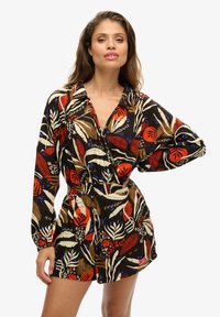 Monos de flores negros con patrones vibrantes en rojo, azul y blanco. Mangas sueltas y una cinturilla elástica para un ajuste relajado.