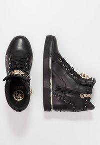 Zapatillas altas negras de piel lisa, con detalles dorados, tachuelas decorativas, cremallera lateral y cuello acolchado para mayor comodidad.