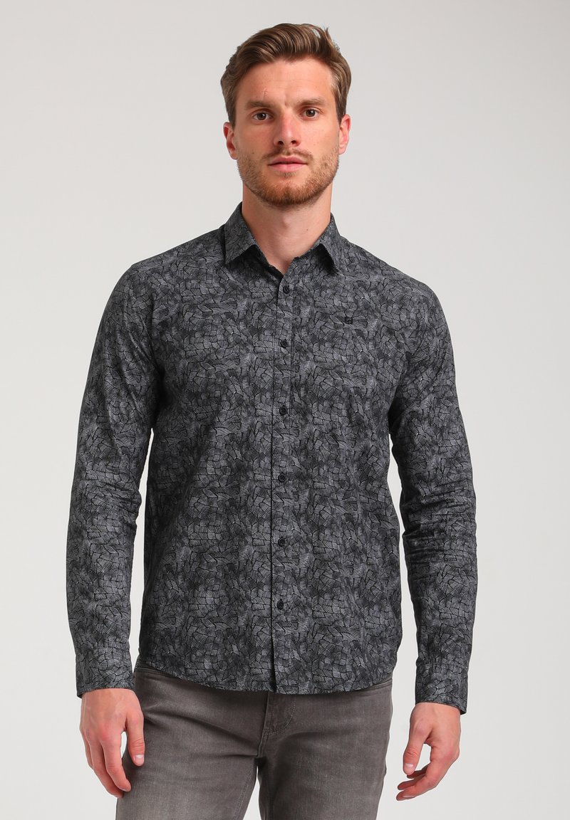 Camicia nera a maniche lunghe, aderente, con un motivo a foglia, colletto a bottoni e tessuto testurizzato, abbinata a pantaloni grigi.