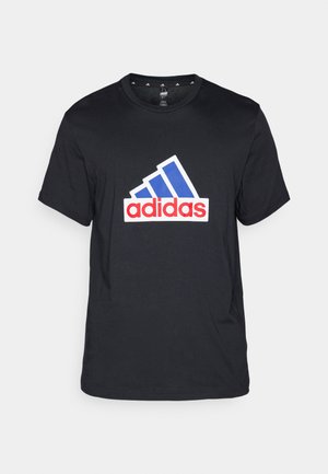 Schwarzes Baumwoll-T-Shirt mit einem großen weißen, blauen und roten Adidas-Logo auf der Brust; kurze Ärmel und runder Halsausschnitt.
