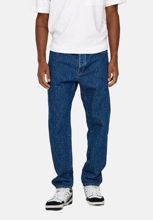 Dark blue denim jeans with a straight-leg cut, featuring a front pocket and a classic waistband. Worn with a white short-sleeve shirt.