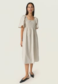 Light beige dress with horizontal stripes, puff sleeves, square neckline, and gathered bodice, paired with black pointed flats.