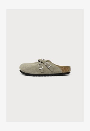 Hellbeige Wildleder-Slipper mit zwei verstellbaren silbernen Schnallen und Kork-Fußbett mit schwarzer Sohle.
