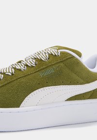Baskets en suède vert olive avec des accents blancs, dotées d'une tige texturée, de lacets contrastants et d'un détail du logo Puma sur le côté.