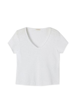 Balta īsroku T-krekls ar V-veida izgriezumu, izklāts plakani ar nedaudz teksturētu audumu un nelielu etiķeti apkakles iekšpusē.