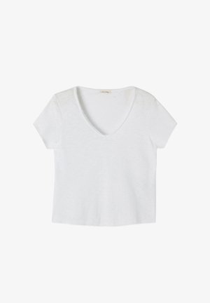 Balta īsroku T-krekls ar V-veida izgriezumu, izklāts plakani ar nedaudz teksturētu audumu un nelielu etiķeti apkakles iekšpusē.