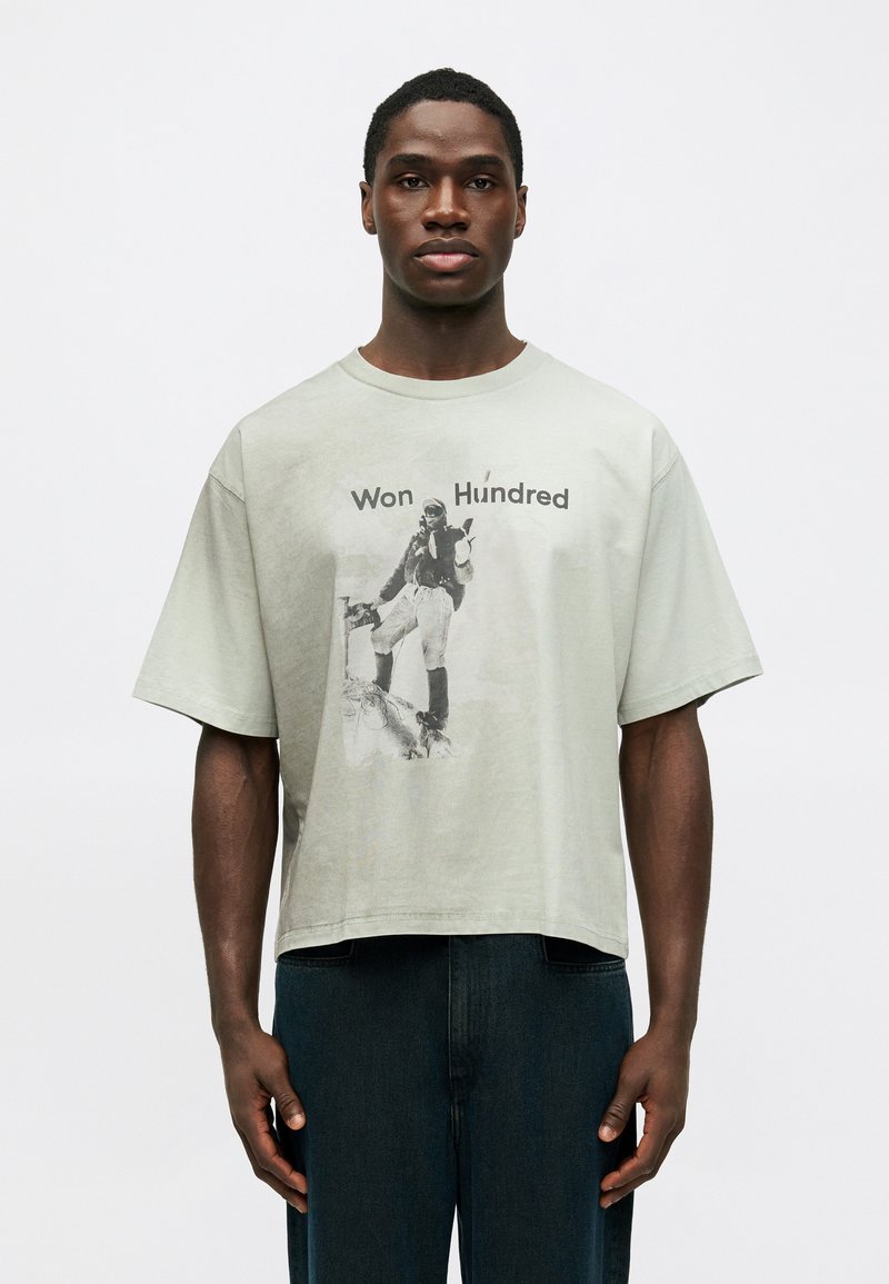 Λαχανί βαμβακερό μπλουζάκι με χαλαρή γραμμή, στρ�ογγυλή λαιμόκοψη και εκτυπωμένο γραφικό ενός μοναδικού σχήματος. Συνδυάζεται με μαύρα τζιν σε αντίθεση.