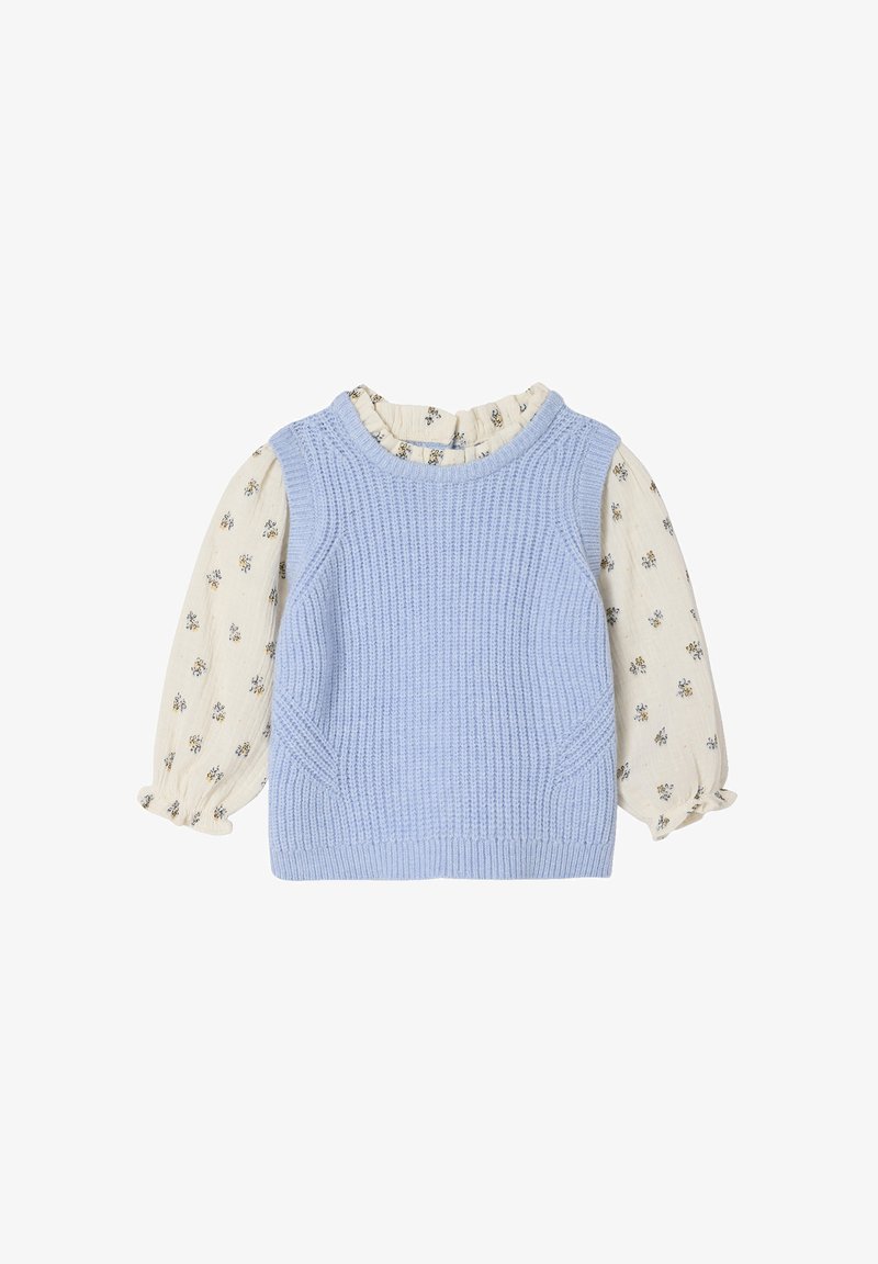 Helles blauer Strickwesten mit geripptem Textur, kombiniert mit einer cremefarbenen Bluse mit Blumenmuster und Puffärmeln.