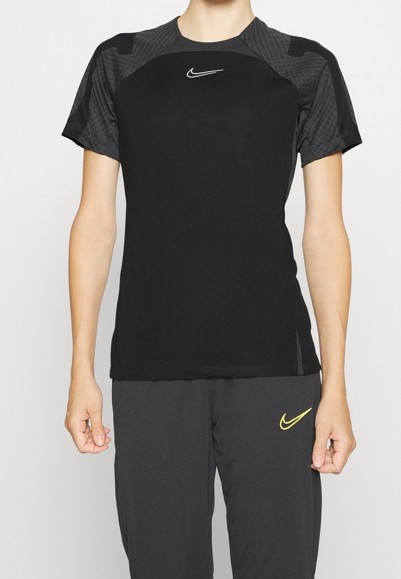 Svart t-shirt med kort ärm avsedd för träning, med texturerade axlar. Den har en vit Nike-logga på bröstet och en åtsittande design.