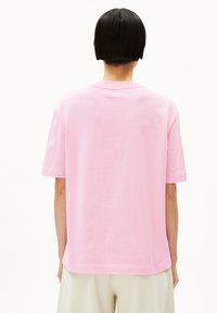 Roze katoenen T-shirt met een ronde hals, korte mouwen en een ontspannen pasvorm. Glad van textuur, zonder zichtbare patronen of accenten, en een eenvoudige achterkant.