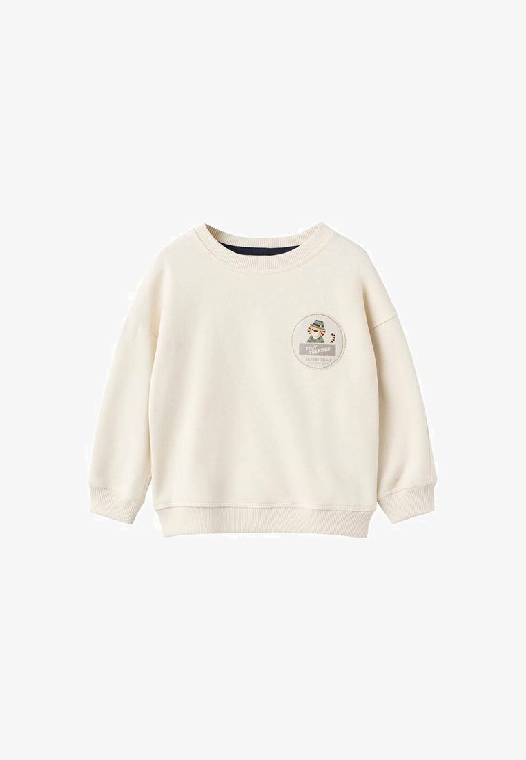 Felpa a maniche lunghe color crema per bambini, con collo a giro e un piccolo patch tondo che presenta una tigre dei cartoni animati e la scritta "Tiny Trekker Safari Trail."