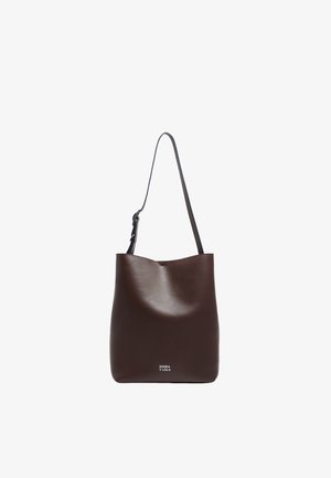 Bruine leren tote bag met een gladde textuur, licht gebogen bovenkant en een verstelbare schouderriem. Voorzien van een wit logo aan de onderkant.