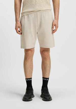 Beige atletikshorts med en lätt och andningsbar textur. Har ett elastiskt midjeband och subtil perforerad detaljering. Matchas med svarta strumpor.