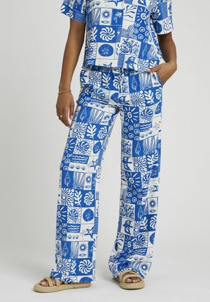 Ensemble deux pièces avec des motifs bleus et blancs représentant la vie marine, des feuilles et des formes géométriques ; top ample et pantalons larges.