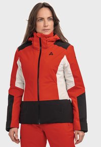 Rote, schwarze und weiße Skijacke mit hohem Kragen, Reißverschluss und gemustertem Farbblockdesign. Mit Logo auf der Brust und der Schulter.