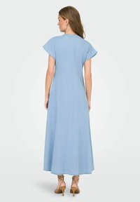 Ljusblå denim maxiklänning med korta ärmar, en figurnära bodice och en svävande kjol. Utmärkande för sin mjuka textur och enkla design.