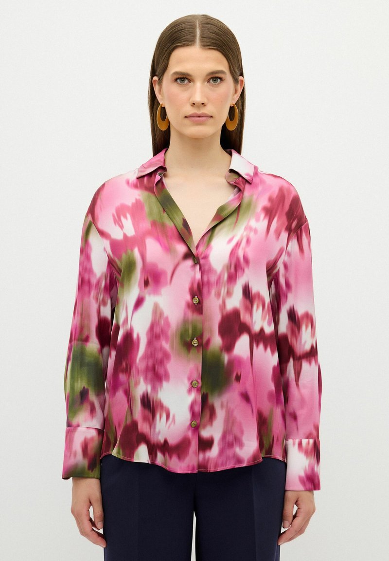 Blusa de seda con un patrón floral en tonos rosa, verde y blanco, con cuello, cierre de botones en la parte delantera y mangas largas.