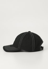 Black baseball cap with white stitching, curved visor, and adjustable back strap. Fabric is soft with a textured appearance.