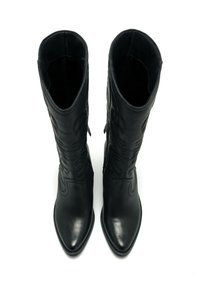 Bottes noires en cuir jusqu'au genou avec un bout pointu, des coutures décoratives et une texture lisse, présentant un empiècement ajusté et sans matériel visible.