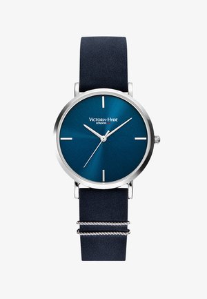 Montre ronde en argent avec un cadran bleu texturé, des index horaires en argent et un bracelet en cuir bleu marine avec des bandes argentées.