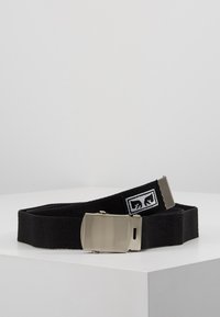 Cinturón negro trenzado hecho de material duradero, que presenta una hebilla metálica plateada y un parche con el logotipo que incluye un diseño gráfico.
