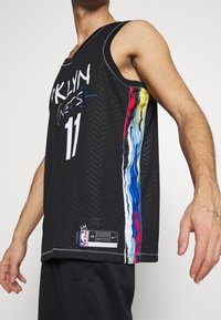 Black basketball jersey with "BROOKLYN NETS" printed in white. Features multicolored stripes on the side and a textured chevron pattern.