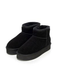 Para czarnych zimowych butów za kostkę z miękką zamszową cholewą i grubymi gumowymi podeszwami na białym tle.