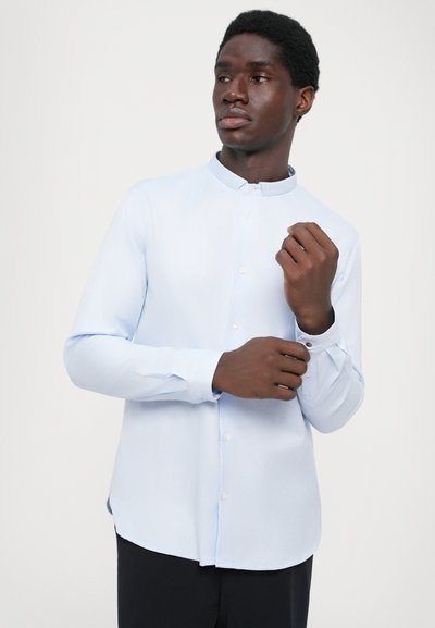 Jasnoniebieska, długosleeve'owa koszula z kołnierzem stojącym i zapięciem na guziki. Gładka tekstura i subtelny połysk, w połączeniu z ciemnymi spodniami.