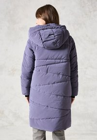 Abrigo acolchado en lavanda, con capucha y líneas de acolchado diagonales. Textura suave, diseño hasta las rodillas, con mangas largas y un corte relajado.