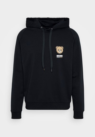 Juodas džemperis su minkšta medžiaga, turintis priekinę kišenę ir meško grafiką ant krūtinės su tekstu "MOSCHINO UNDERWEAR". Su raišteliu reguliuojama kapučino.