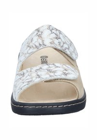 Valkoiset sandaalit, joissa on teksturoidut, keinonahkaiset hihnat, joissa on poimutettu kuvio, avoin kärki, säädettävät tarrakiinnitykset ja pehmustettu pohjallinen.