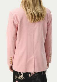 Rosa kordfloddröja med vertikala ribbningar, har en ryggsöm och fyra guldknappar på varje ärm. Slank passform.