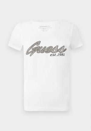 Baltos medvilnės marškinėliai trumpomis rankovėmis su juodu ir sidabriniu „Guess“ logotipu ir tekstu „est. 1981“ priekyje.
