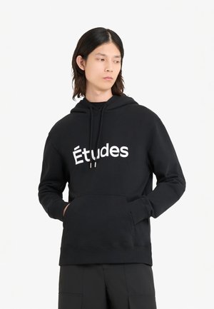 Sweat à capuche noir avec logo "Études" blanc, poche kangourou et poignets côtelés. Fabriqué en mélange de coton doux.