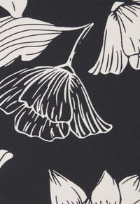 Schwarzer Stoff mit einem weißen Blumenmuster, das umrandete Blütenblätter und detaillierte Adern zeigt und einen starken Kontrast in den Mustern schafft.