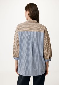Camicia a righe con design colletto. Presenta righe verticali beige e blu, maniche a tre quarti e una vestibilità ampia.