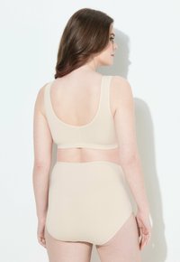 Beige BH und hochgeschnittenes Slip-Set. Weicher, dehnbarer Stoff mit nahtlosem Design. Breite Träger und bequemer Schnitt für eine glatte Silhouette.