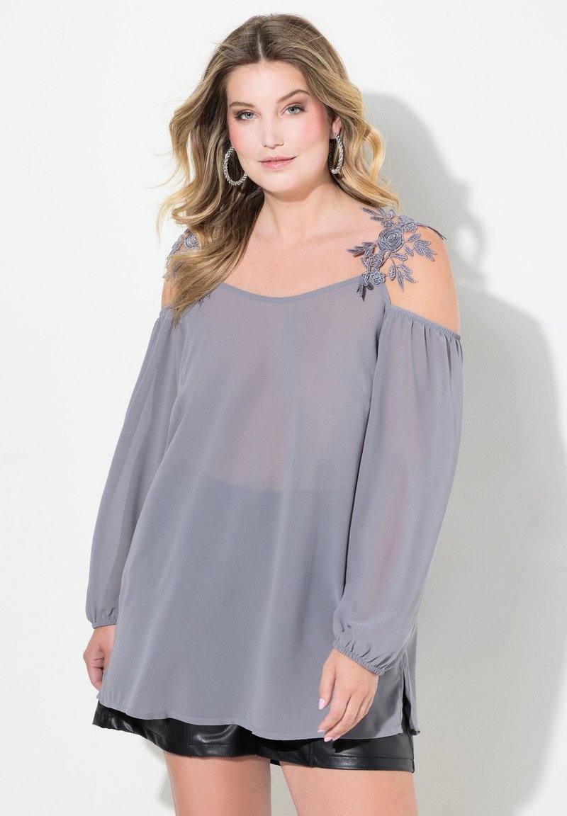 Blusa gris sin hombros con mangas largas, bordado floral en los hombros, tela ligera y un diseño suelto y fluido.