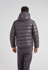 Chaqueta tipo puffer en gris oscuro, con capucha, diseño acolchado horizontal y textura brillante. Mangas largas con puños elásticos.