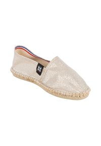 Chaussure espadrille beige clair avec semelle tissée, modèle à enfiler, et petite étiquette noire avec logo sur le côté.