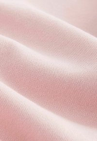 Weicher rosa Strickstoff mit glatter Textur, der ein dezentes Rippenmuster aufweist. Das Material wirkt leicht und flexibel.