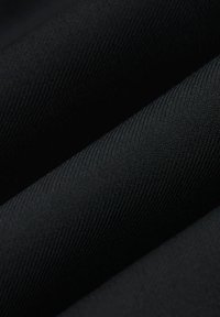 Czarna tkanina o gładkiej fakturze i diagonalnym prążkowanym wzorze, charakteryzująca się jednolitym kolorem w wielu fałdach. Trwały materiał.