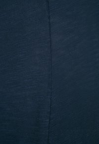 Marineblauer Strickstoff mit glatter Textur zeigt feine, subtil variierende Linien. Das Design verfügt über eine Naht in der Mitte, die die Form hervorhebt.