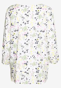 Blusa floreale con maniche a tre quarti, caratterizzata da uno sfondo bianco, fiori multicolori in rosa, giallo e verde, con una morbida trama di tessuto.