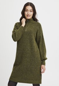Abito verde in maglia lunghezza al ginocchio con colletto alto e zip a metà. Texture morbida e maniche ampie, che offrono una vestibilità comoda.